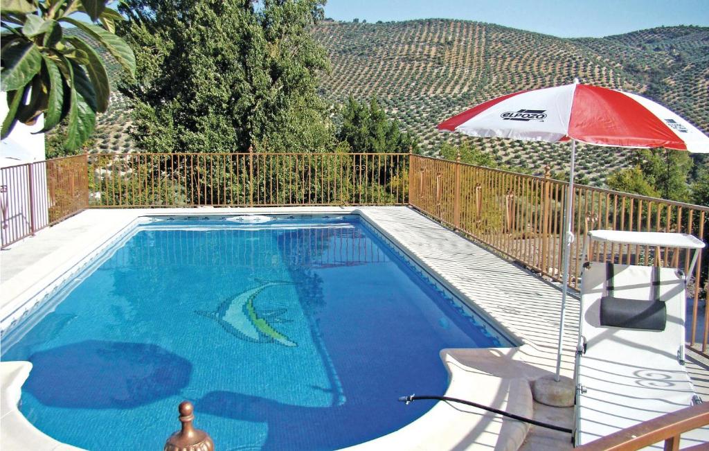 una piscina con sombrilla junto a una valla en Cozy Home In Iznjar With House A Mountain View, en Iznájar