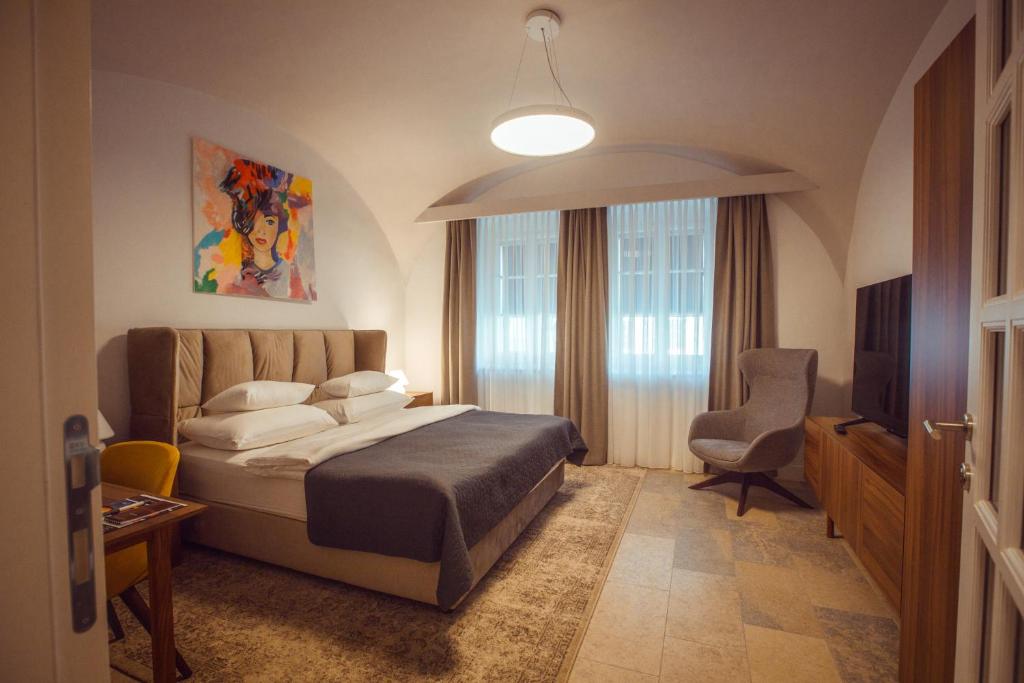 a bedroom with a bed and a chair and a television at Apartman Boutique Tvrđa in Osijek