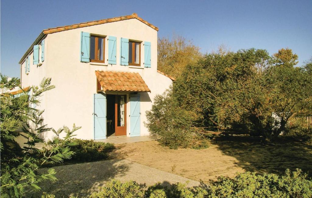 ラ・トランシュ・シュル・メールにある3 Bedroom Lovely Home In La Tranche Sur Merの青い窓と木々が特徴の小さな白い家