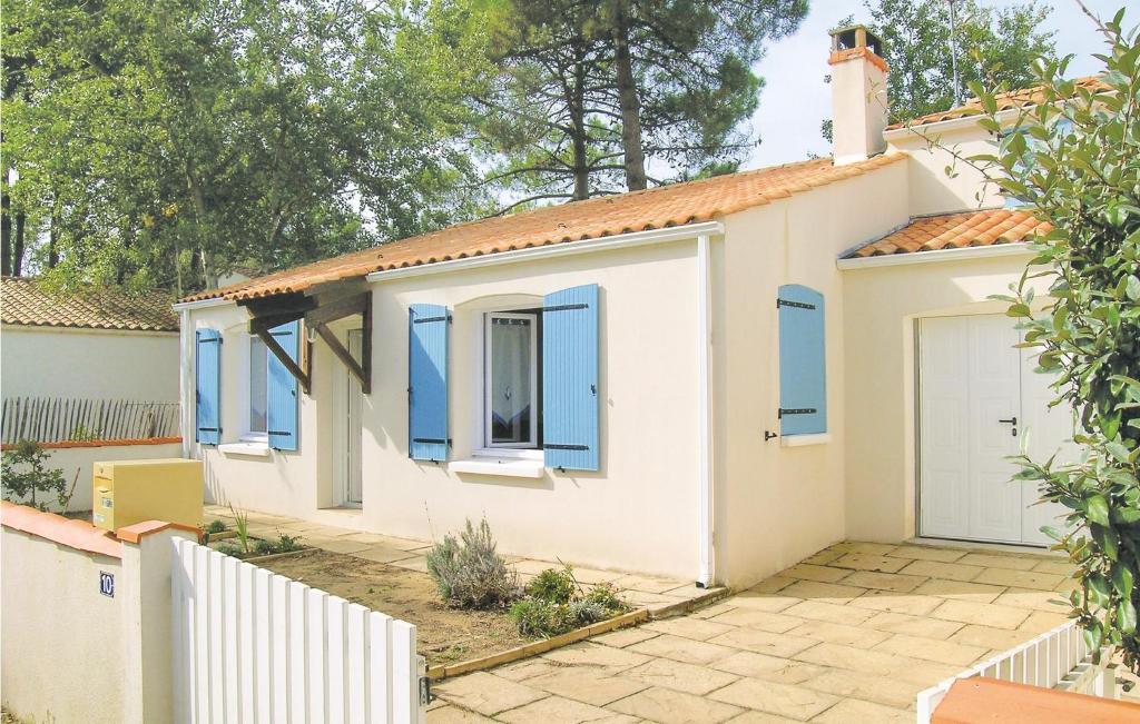 a white house with blue windows and a driveway at Amazing Home In La Tranche Sur Mer With Kitchen in La Tranche-sur-Mer