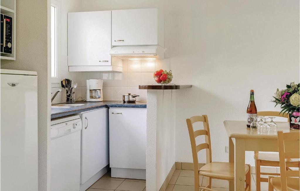 a kitchen with white cabinets and a table with chairs at Le Hameau De Peemor Pen in Morgat