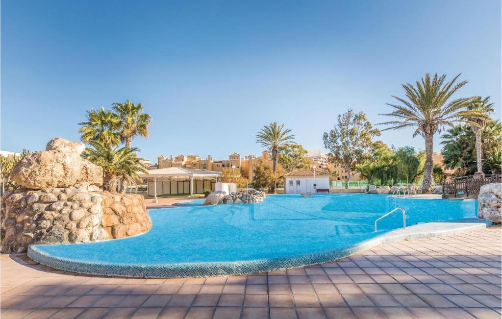 een zwembad in een resort met palmbomen bij Beautiful Apartment In Roquetas De Mar With Kitchen in Roquetas de Mar