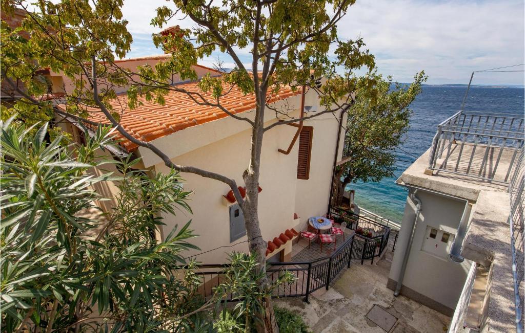 Pet Friendly Apartment In Starigrad With House Sea View في ستاريغراد: منزل به شجرة بجوار المحيط