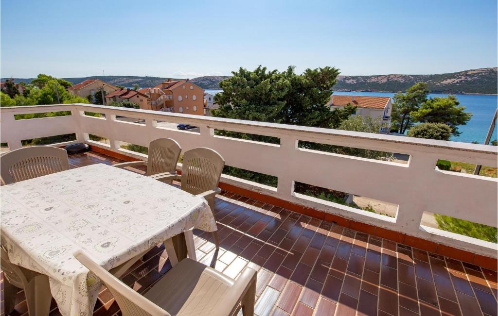 een tafel en stoelen op een balkon met uitzicht op het water bij Lovely Apartment In Stara Novalja With Wifi in Kaštel