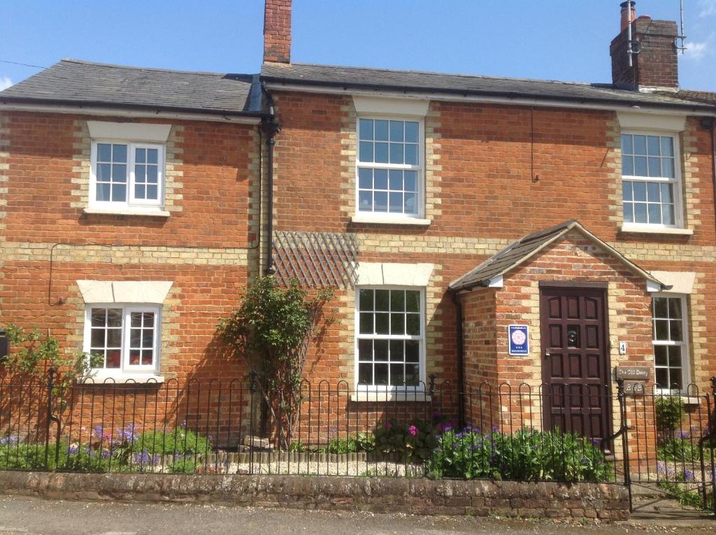 a brick house with a fence in front of it at The Old Dairy in Waddesdon