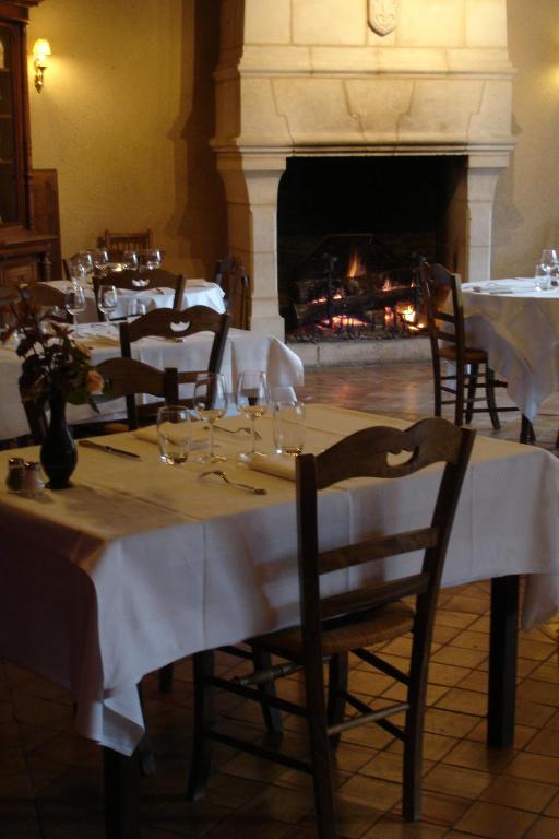 a dining room with tables and chairs and a fireplace at Le Relais du Lyon d&#39;Or in Angles-sur-lʼAnglin