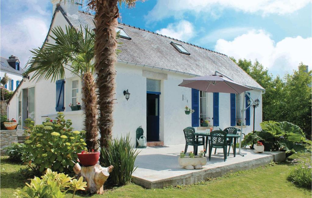 uma casa com uma mesa e cadeiras e um guarda-sol em Cozy Home In La Fort Fouesnant With Kitchenette em La Forêt-Fouesnant