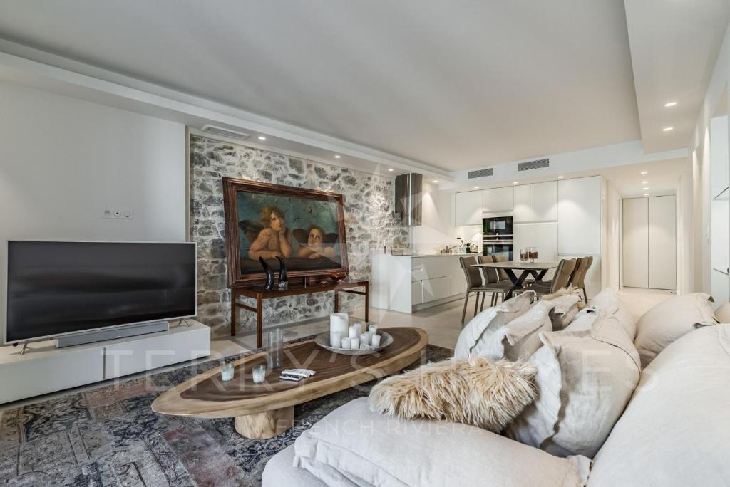 a living room with a white couch and a tv at Paula by Terry&#39;s Homes in Cannes