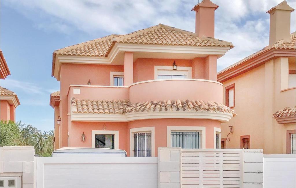 una gran casa naranja con una valla blanca delante de ella en Cozy Home In Cartagena With Kitchenette, en Los Urrutias