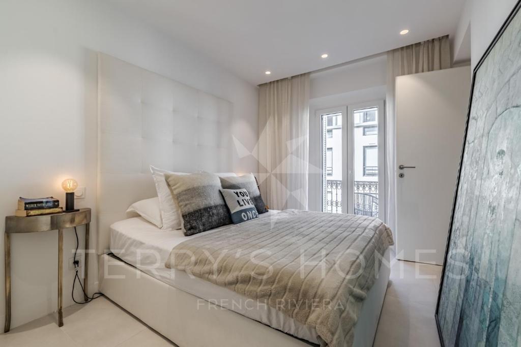a white bedroom with a bed and a window at Paula by Terry&#39;s Homes in Cannes