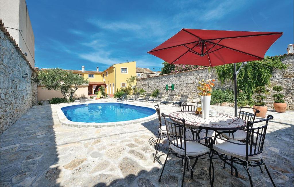 a table with a red umbrella next to a pool at Cozy Home In Pakostane With Kitchen in Pakoštane