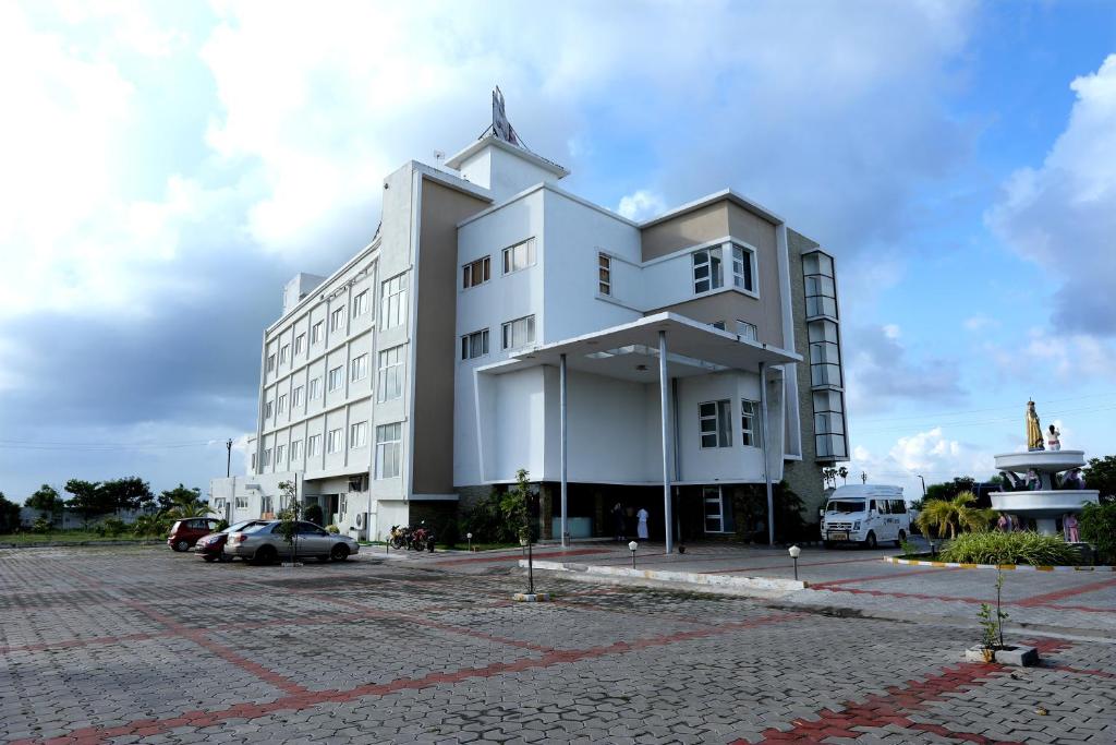 a white building with a cross on top of it at Hotel Queens Inn Velankanni in Velānganni