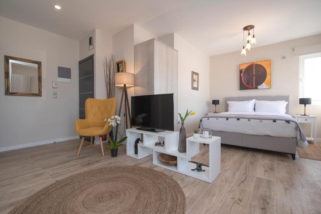 a white bedroom with a bed and a tv at Chrysalis 2 in Kos