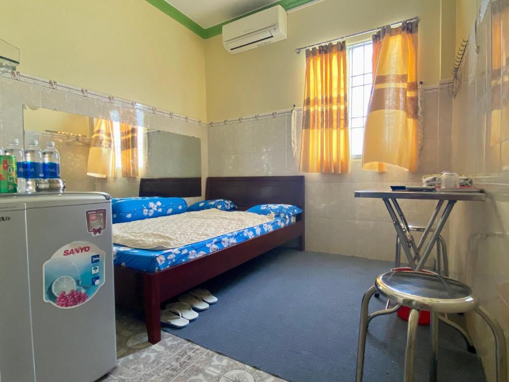 Cette petite chambre comprend un lit et un réfrigérateur. dans l'établissement Khách Sạn Ngọc Cường, à Bạc Liêu