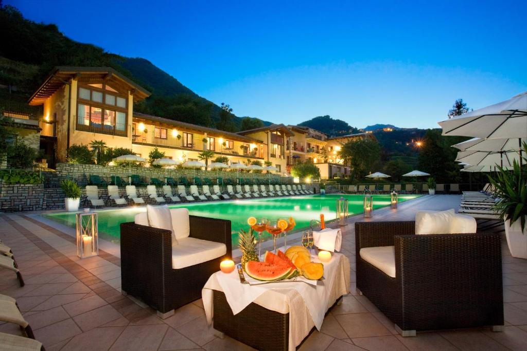 einen Pool mit Stühlen und einen Tisch mit Obst darauf in der Unterkunft Residence Delle Rose in Tremosine sul Garda