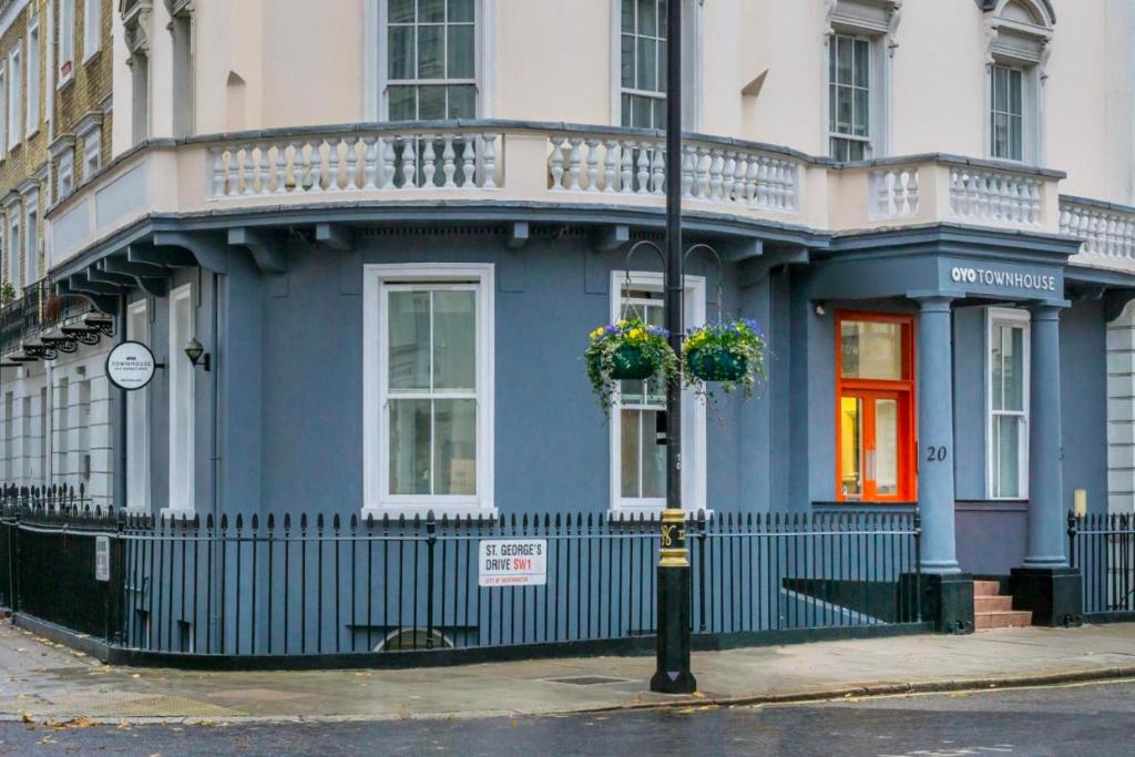 a blue house with flowers on a street at OYO Townhouse New England, London Victoria in London