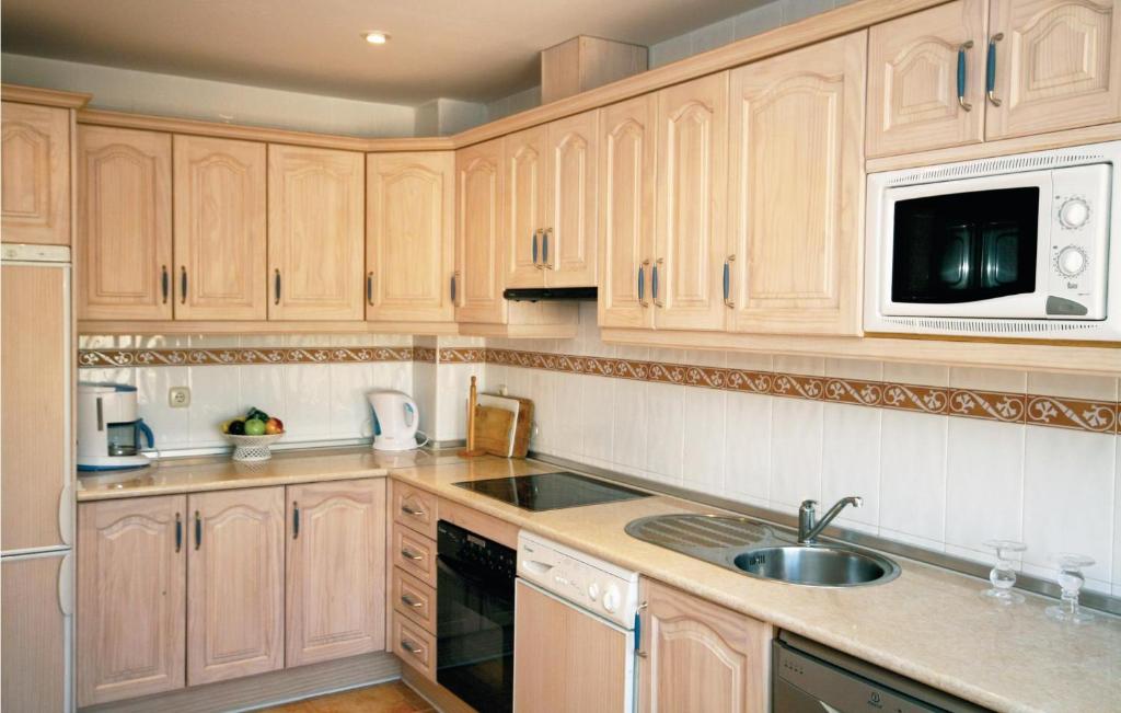 a kitchen with wooden cabinets and a sink and a microwave at Jarales Alpha in Mijas Costa