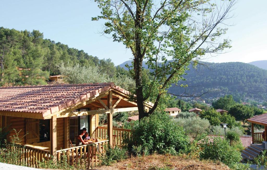 une maison dans les montagnes avec 2 personnes assises sur une terrasse couverte dans l'établissement Les Cottages Varois, à Solliès-Toucas