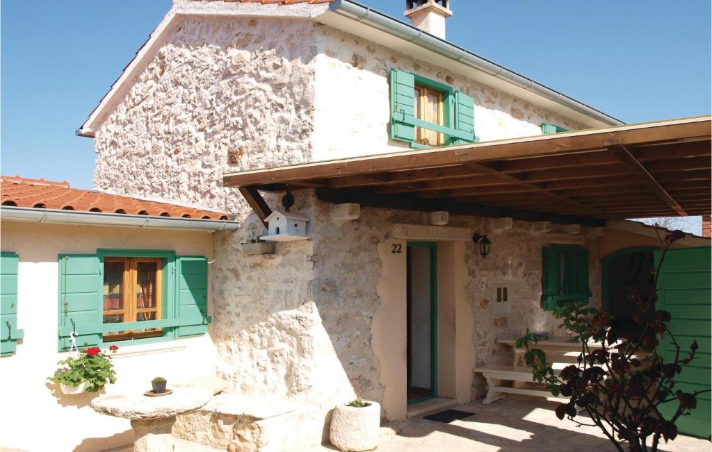 ein Steinhaus mit grünen Fenstern und einer Veranda in der Unterkunft Amazing Home In Jadrija With 2 Bedrooms And Wifi in Jadrija