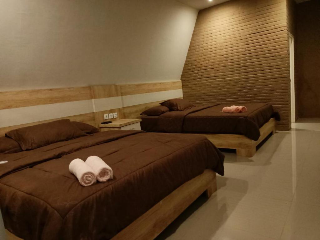 2 Betten in einem Hotelzimmer mit Handtüchern darauf in der Unterkunft Pagupon Camp Syariah in Batu