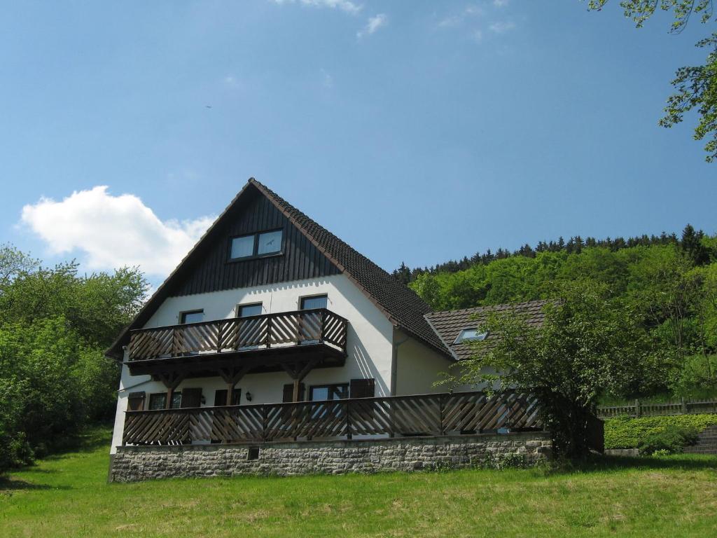 uma grande casa branca com uma varanda numa colina em Nice holiday home near ski area em Medebach