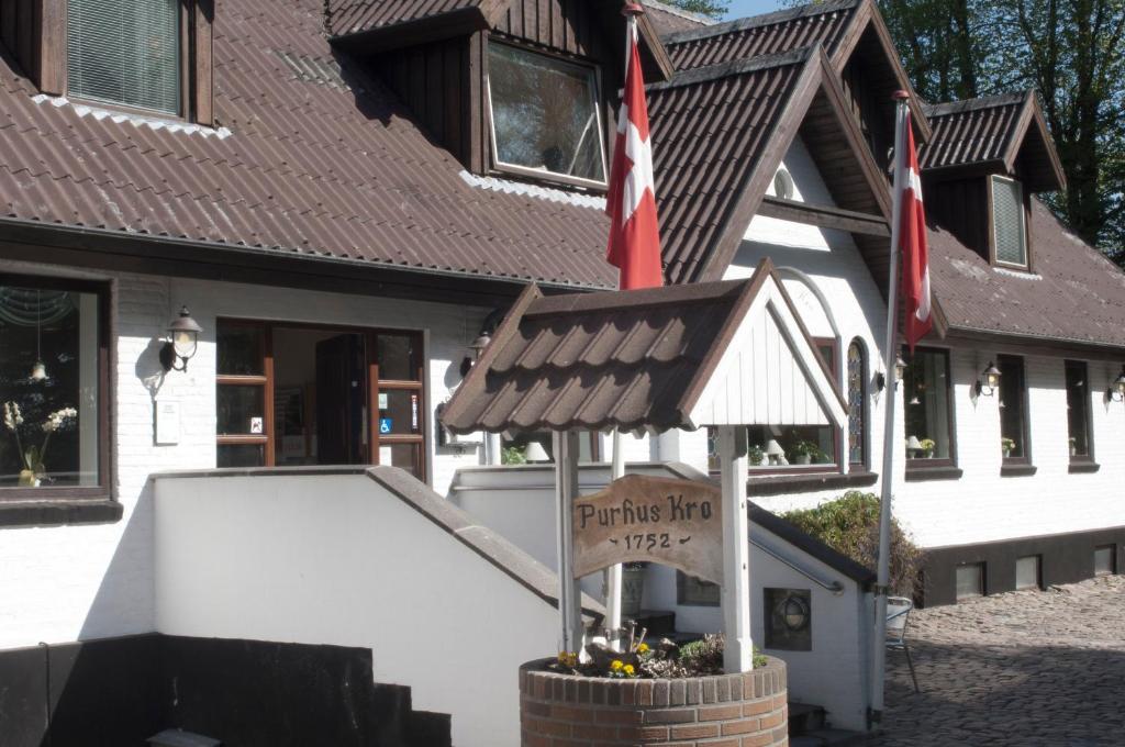 a building with a sign in front of a house at Purhus Kro in Fårup