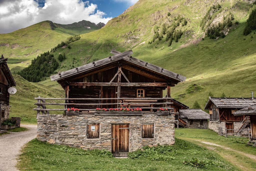 a stone building with red flowers on a mountain at Lechnerhütte Fane Alm in Valles