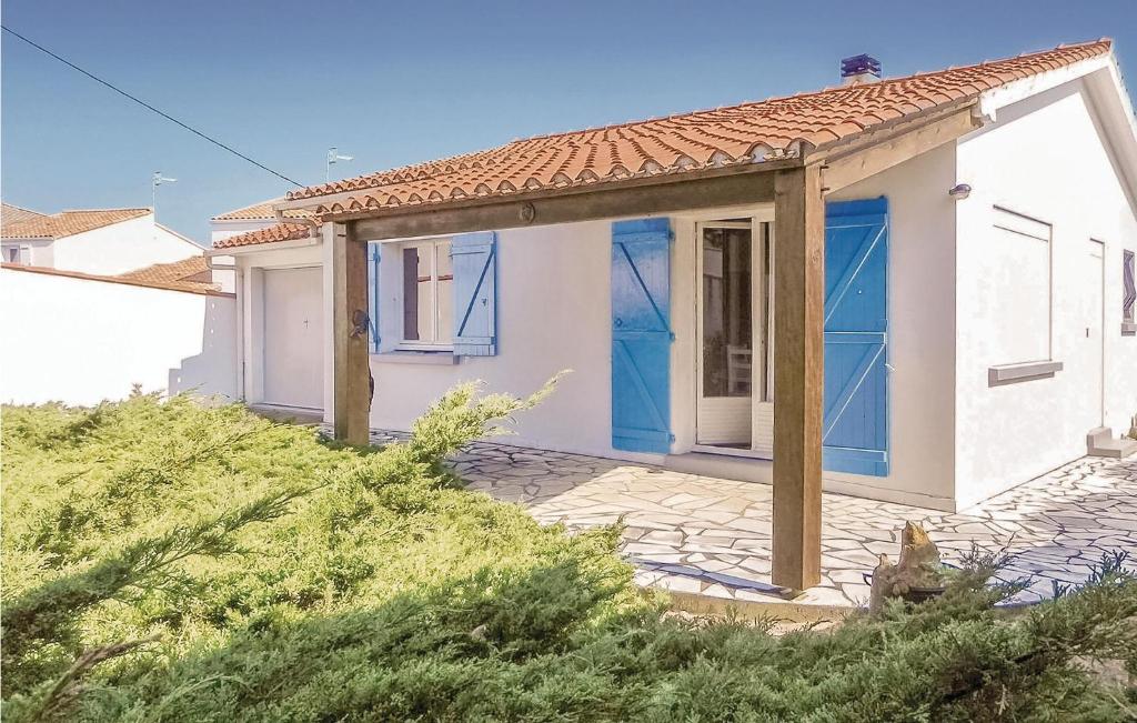 een klein wit huis met blauwe deuren bij Cozy Home In La Tranche-sur-mer With Kitchenette in La Tranche-sur-Mer