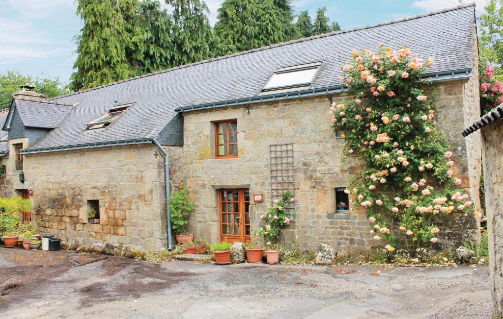 una vieja casa de piedra con un árbol floreciente delante de ella en Stunning Home In Melrand With Kitchenette, en Melrand
