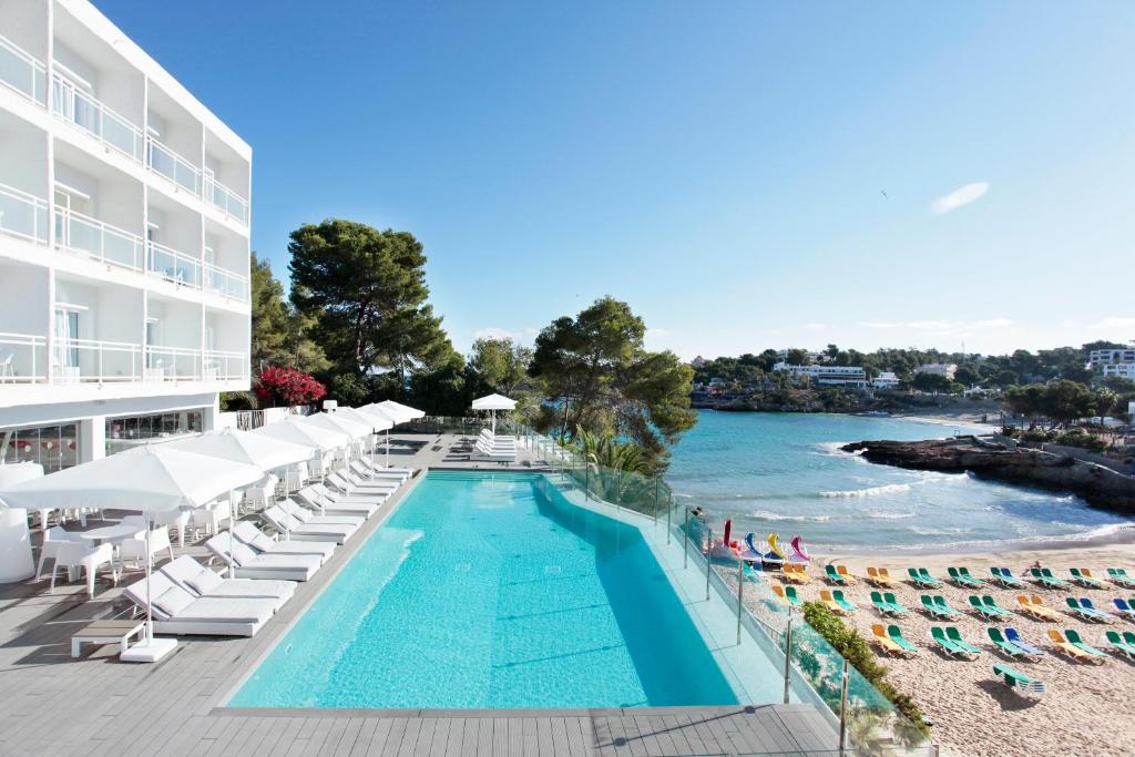 a swimming pool with lounge chairs and a hotel at Grupotel Ibiza Beach Resort - Adults Only in Portinatx