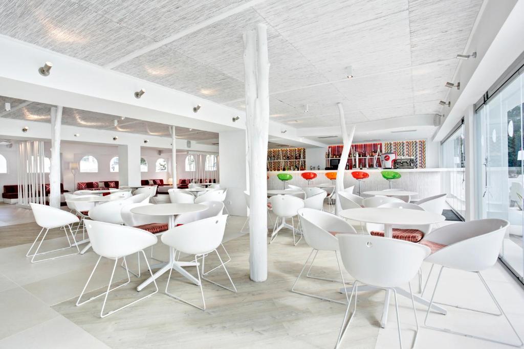 a restaurant with white tables and white chairs at Grupotel Ibiza Beach Resort - Adults Only in Portinatx
