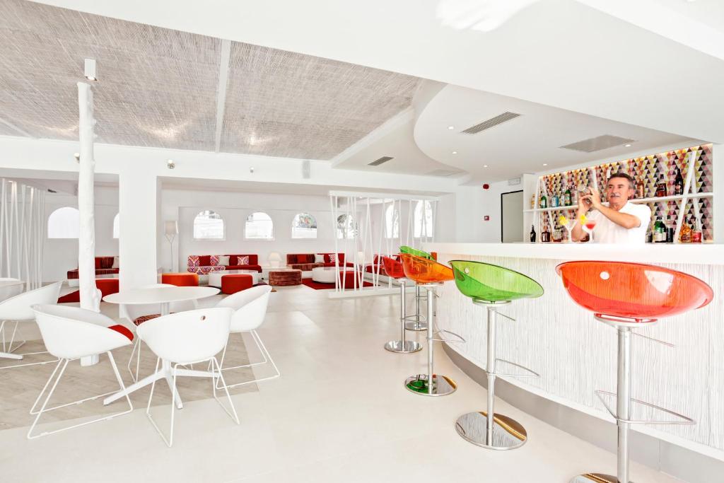 a dining room with colorful chairs and a bar at Grupotel Ibiza Beach Resort - Adults Only in Portinatx