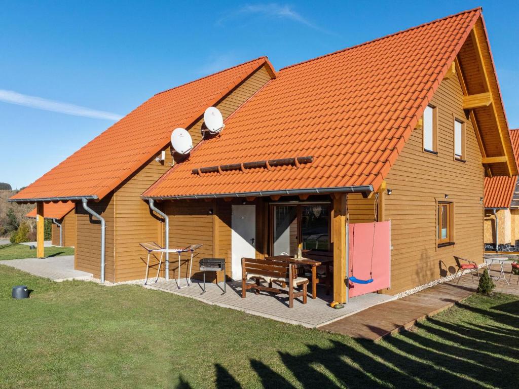 a wooden house with an orange roof with a table at Holiday home in Hasselfelde with garden in Hasselfelde