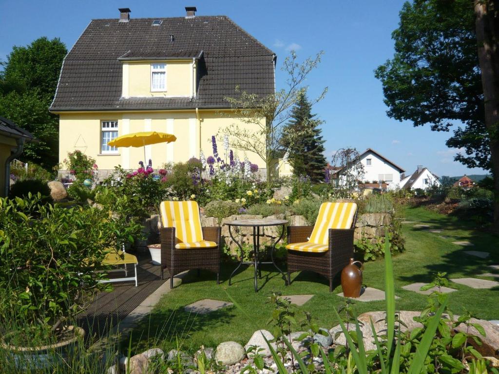 un jardín con 2 sillas y una mesa y una casa en Villa with a view of the Weserbergland, en Bad Pyrmont