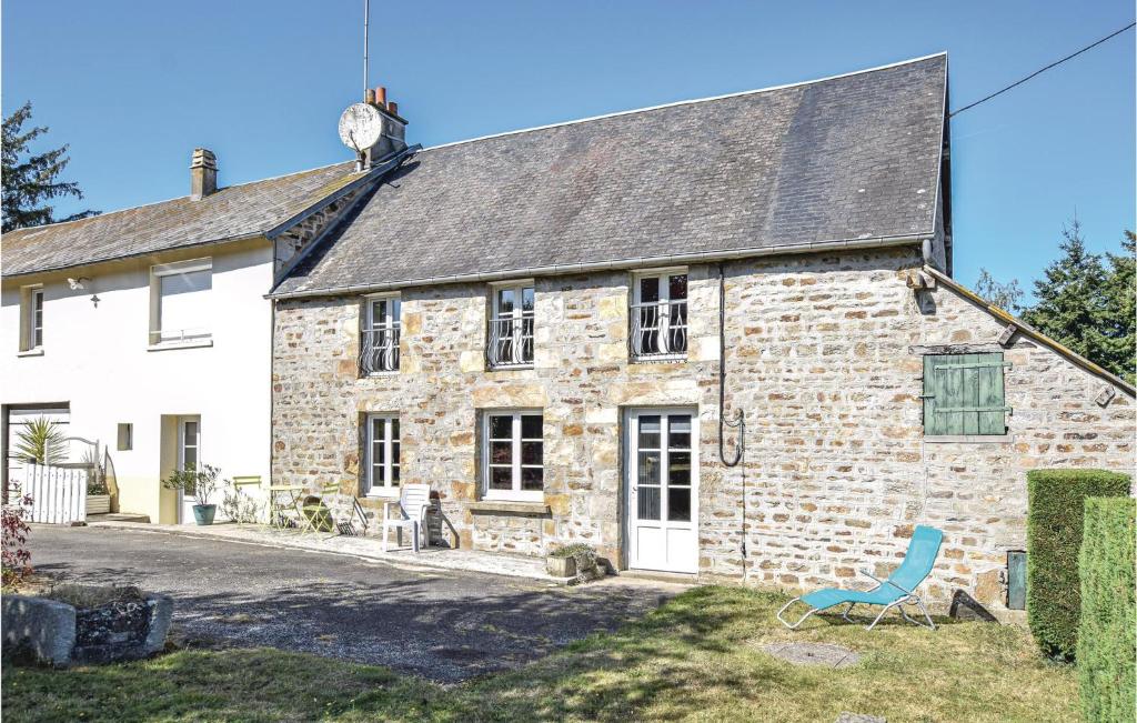 an old stone house with a clock on the roof at Amazing Home In Lonlay Labbaye With 3 Bedrooms in Lonlay-lʼAbbaye