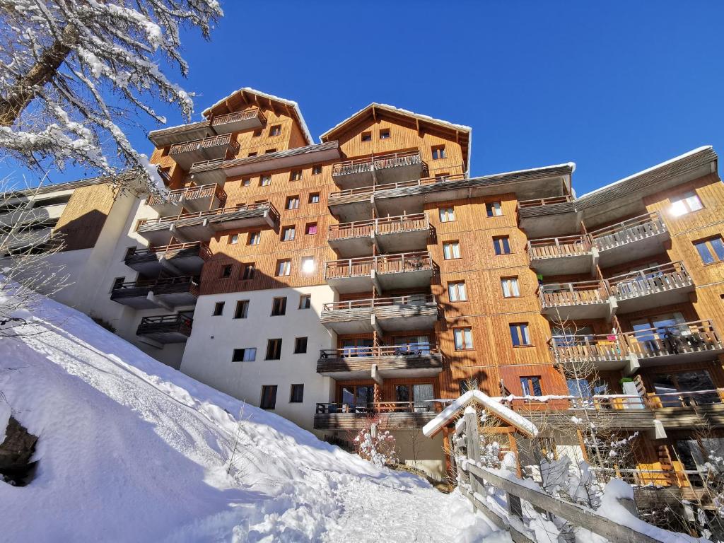 Un bâtiment dans la neige avec un snowboard devant lui dans l'établissement le hameau des ecrins, à Puy-Saint-Vincent