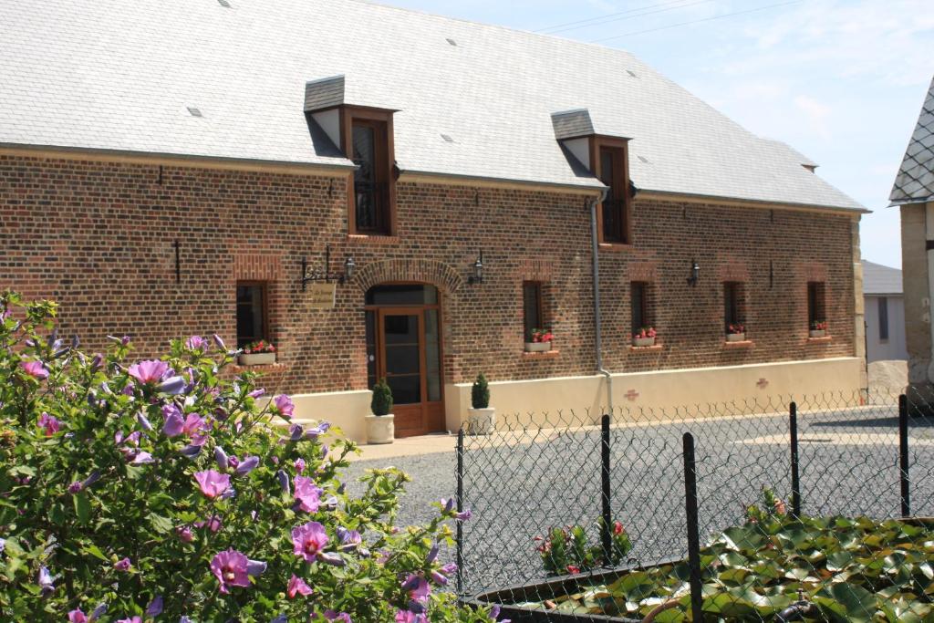 a brick building with a fence and flowers at La Grange de Boulaines in Méru