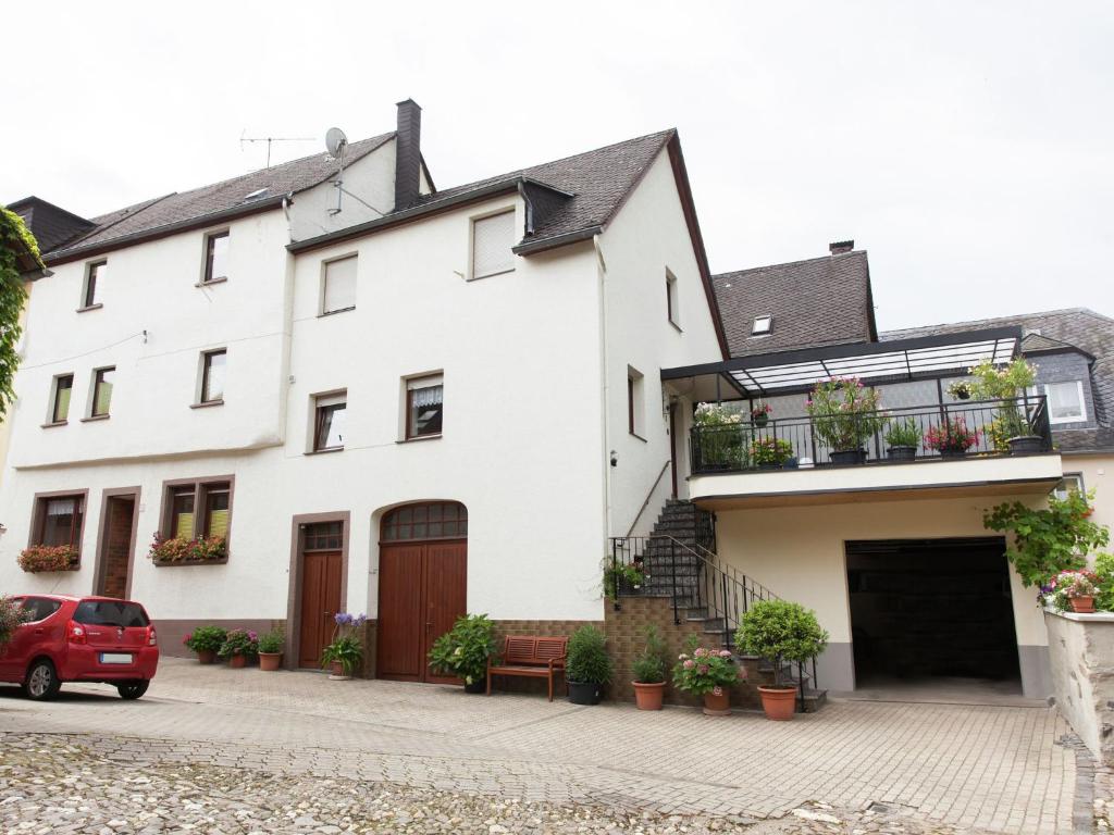 a white house with a red car parked in front of it at Pleasant Apartment in Ernst bei Cochem with Garden in Ernst