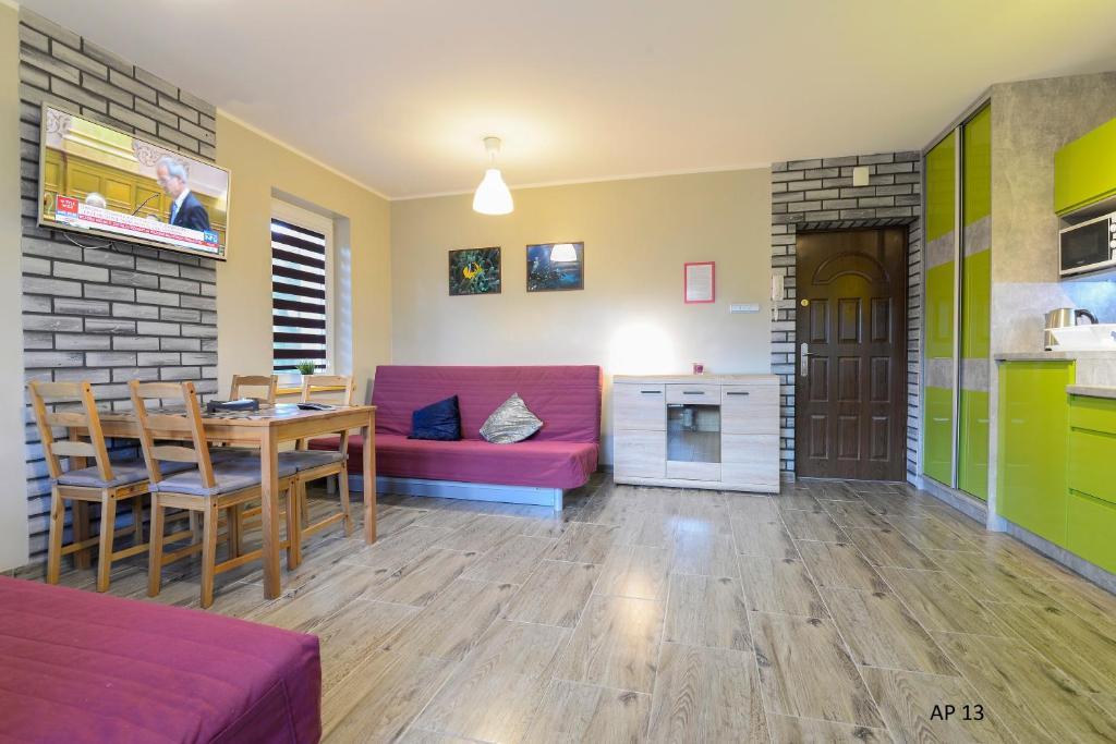 sala de estar con mesa y sofá rojo en Apartament Luba, en Krynica Morska