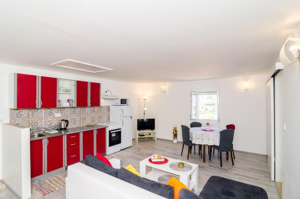 a kitchen and living room with red cabinets and a table at Apartment Jasmin in Dubrovnik