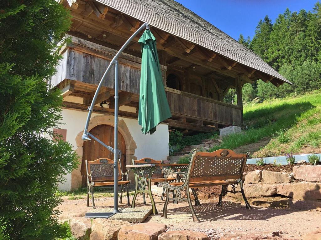 a table and chairs with an umbrella in front of a house at Holiday home in the Black Forest with sauna in Berneck