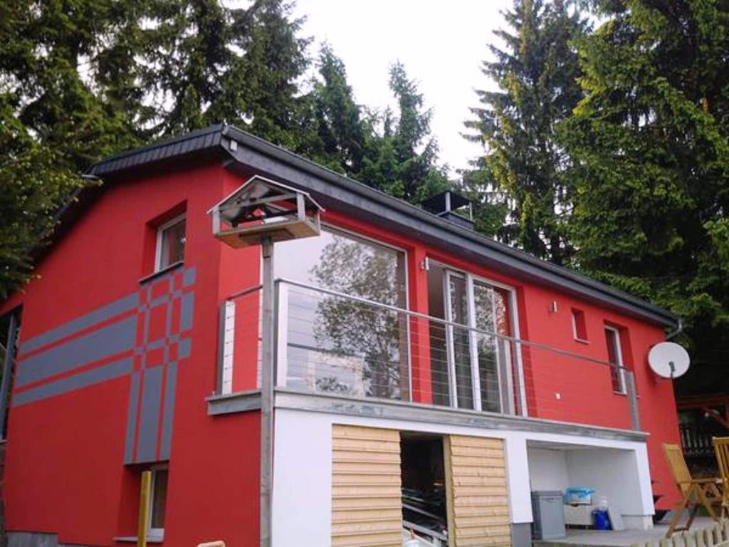 een rood-wit huis met bomen op de achtergrond bij Bright holiday home in Schnett with private garden in Schnett