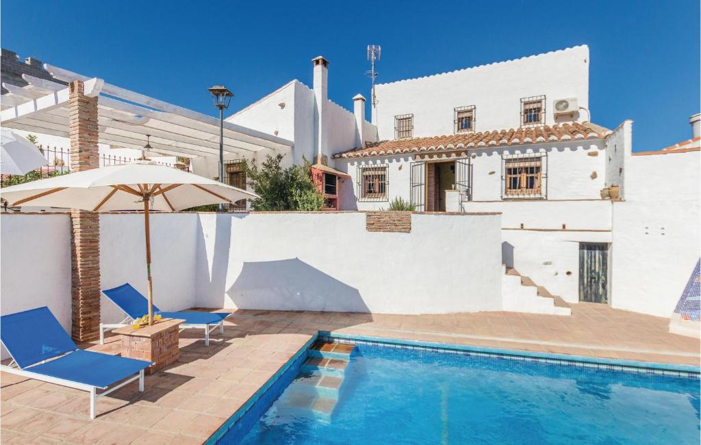 una piscina con 2 sillas y una sombrilla junto a una casa en Stunning Home In Almachar With 5 Bedrooms, Wifi And Outdoor Swimming Pool, en Almáchar