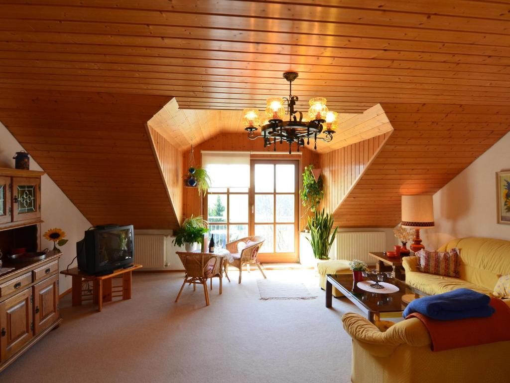a large living room with a wooden ceiling with a chandelier at Flat with sauna in the Bavarian Forest in Waldkirchen