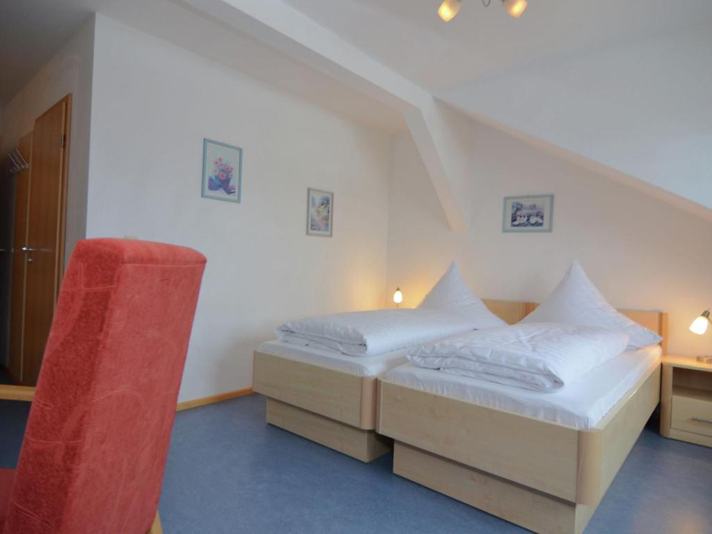a bedroom with two beds and a red chair at Wohnung in Rotthalmünster mit Garten in Andriching