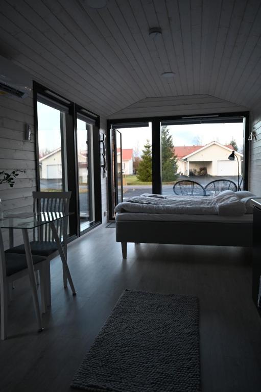 a bedroom with a bed and a chair and windows at Willa Rauha F in Lumijoki