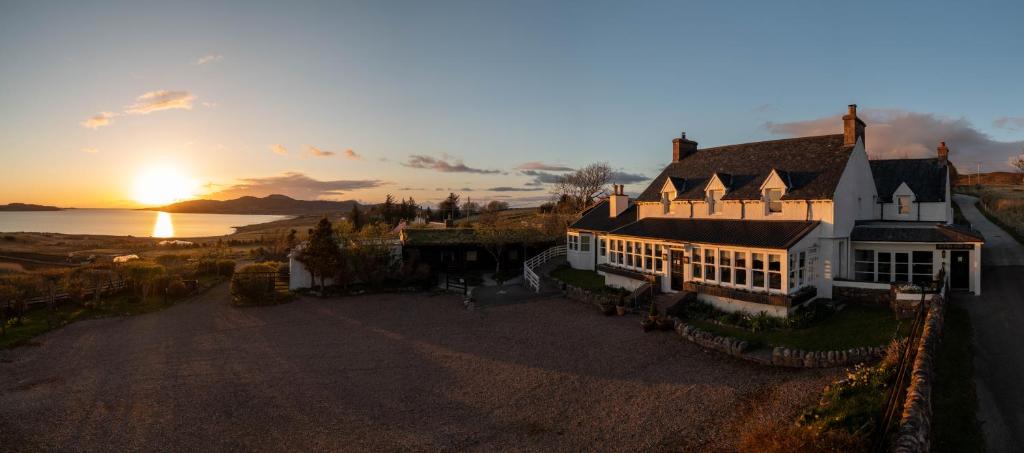 une vue aérienne sur une maison avec le coucher du soleil en arrière-plan dans l'établissement Summer Isles Hotel, à Achiltibuie