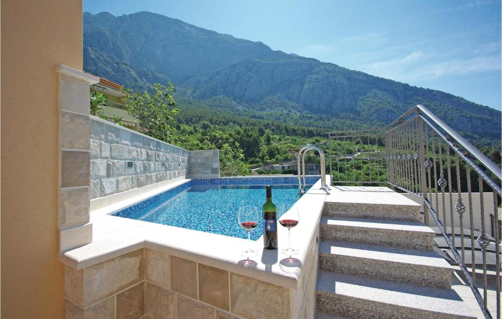 a swimming pool with a bottle of wine next to a house at Cozy Home In Makarska With Kitchen in Makarska