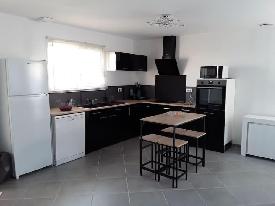 a kitchen with black and white appliances and a table at Villa en bordure de forêt . in Onesse-et-Laharie