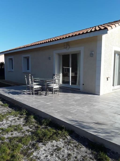 un patio avec une table et des chaises devant une maison dans l'établissement Villa en bordure de forêt ., à Onesse-et-Laharie